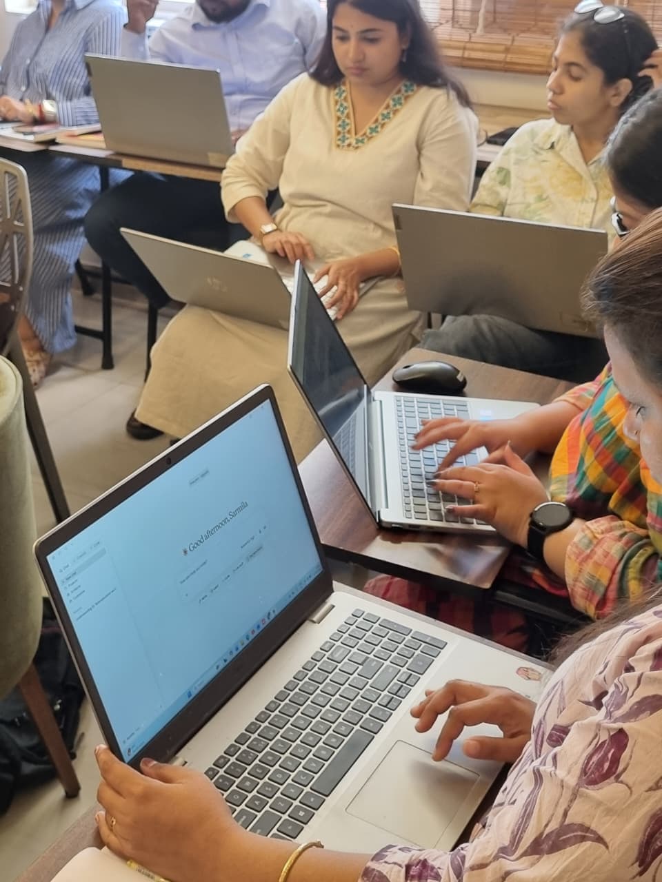 Participants working in Claude on their own laptops during a session